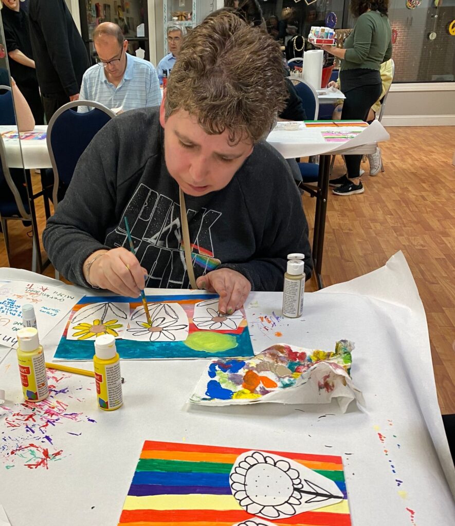 A woman colors paints flowers on paper over a gorgeous water color paint.